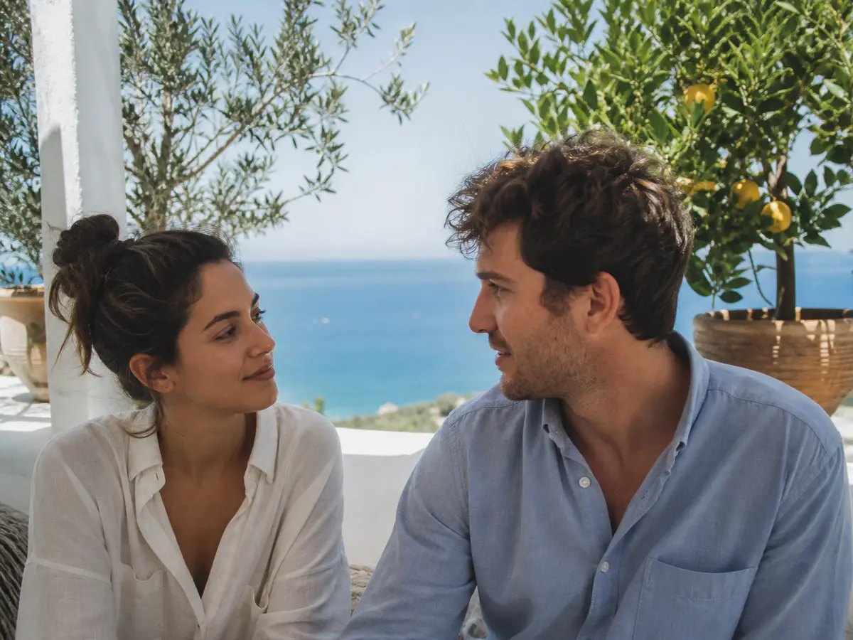 A couple sharing a quiet moment on a shaded terrace above the Mediterranean